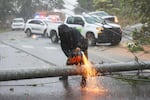 A worker cuts an electricity pole that was downed by Hurricane Fiona as it blocks a road in Cayey, Puerto Rico, Sunday.