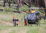 Searchers exit a Brim helicopter after finding 69-year-old Harry Burleigh alive on Sunday, May 23, 2021.
