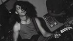 A black and white photo of a man with long hair and a guitar.