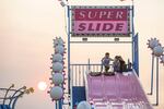 A boy stands atop the Super Slide as a smoky sun sets on Salem.