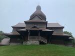 Holy Trinity Particular Ukrainian Catholic Church is a wooden building with a stone foundation and sits atop green grass.