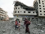 Palestinians walk through debris amid massive destruction from Israeli airstrikes in Gaza City's al-Rimal district, on Tuesday, Oct. 10, 2023.
