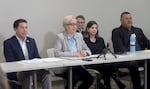 Kotek is seated at a folding table while talking in a conference room. Sixkiller sits to the left of her as he listens to her talk.