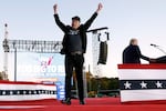 Musk throws both arms in the air and leaves the stage after addressing a campaign rally with Donald Trump on Oct. 5 in Butler, Pa. The stage is decorated in red, white and blue.