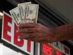 Maher Diab holds up cash before buying lottery tickets at Bluebird Liquor, Friday, Oct. 28, 2022, in Hawthorne, Calif. Saturday's jackpot projected winnings of an estimated $825 million is the fifth-highest in U.S. history.