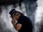A man cools off at a temporary misting station deployed by the city in the Downtown Eastside due to a heat wave, in Vancouver, British Columbia, Aug. 16, 2023.