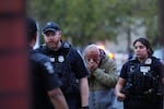 An unidentified man is led into the scene by police after they responded to a shooting at Seattle Center during the Bite of Seattle food festival Sunday, July 26, 2026, in Seattle, Wash.