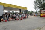 Residents wait in line with gas cans at a Gas Plus gas station in the aftermath of Hurricane Helene Sunday in North Augusta, S.C.