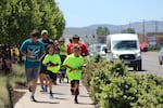 Runners carry carved wooden salmon as they run down South 6th Street in Klamath Falls, Oregon on their way to the Klamath River's headwaters in Southern Oregon on May 28, 2017
