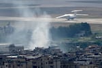 A plane take off from Rafik Hariri international airport as smoke of a past Israeli airstrike still rise from Dahiyeh, in Beirut, Lebanon, Monday, Oct. 14, 2024.