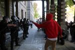 Micah Rhodes, an organizer with Don't Shoot PDX, faces police in riot gear stationed outside city hall.