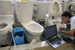 An employee checks the water functions of various types of toilets, in the research laboratories of Toto, in Kokura, Japan, 8th August 2005. Toto are a multinational company known for their manufacturing of toilets and washout toilets.