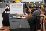 A collection box for gift card donations for TSA workers who have gone unpaid for several weeks, sits near travellers in the main terminal of Denver International Airport Friday, March 20, 2026, in Denver.