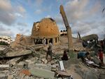 People stand outside a mosque destroyed in an Israeli air strike in Khan Younis, Gaza Strip, Sunday, Oct.8, 2023.