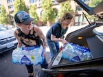 Jamie Inman of Portland., Ore., left, drops off donated cases of water at Blanchet House in Portland, July 3, 2024, as Blanchet House staffer Ava Duckhorn assists. Inman saw Blanchet House’s request for donations on social media and says they “thought this was something our neighborhood needs” and wanted to support the community. Excessive heat is predicted for much of Oregon and Southwest Washington, anticipated for Thursday through at least Sunday.