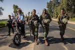 An Israeli activist dressed as a clown rides an electric bike alongside Israeli soldiers accompanying families of the hostages and supporters near the start of the four-day march to Jerusalem on Feb. 28. The activist, who goes by the name "Hashoteret Az-Oolay," regularly attends demonstrations for a variety of issues across Israel.