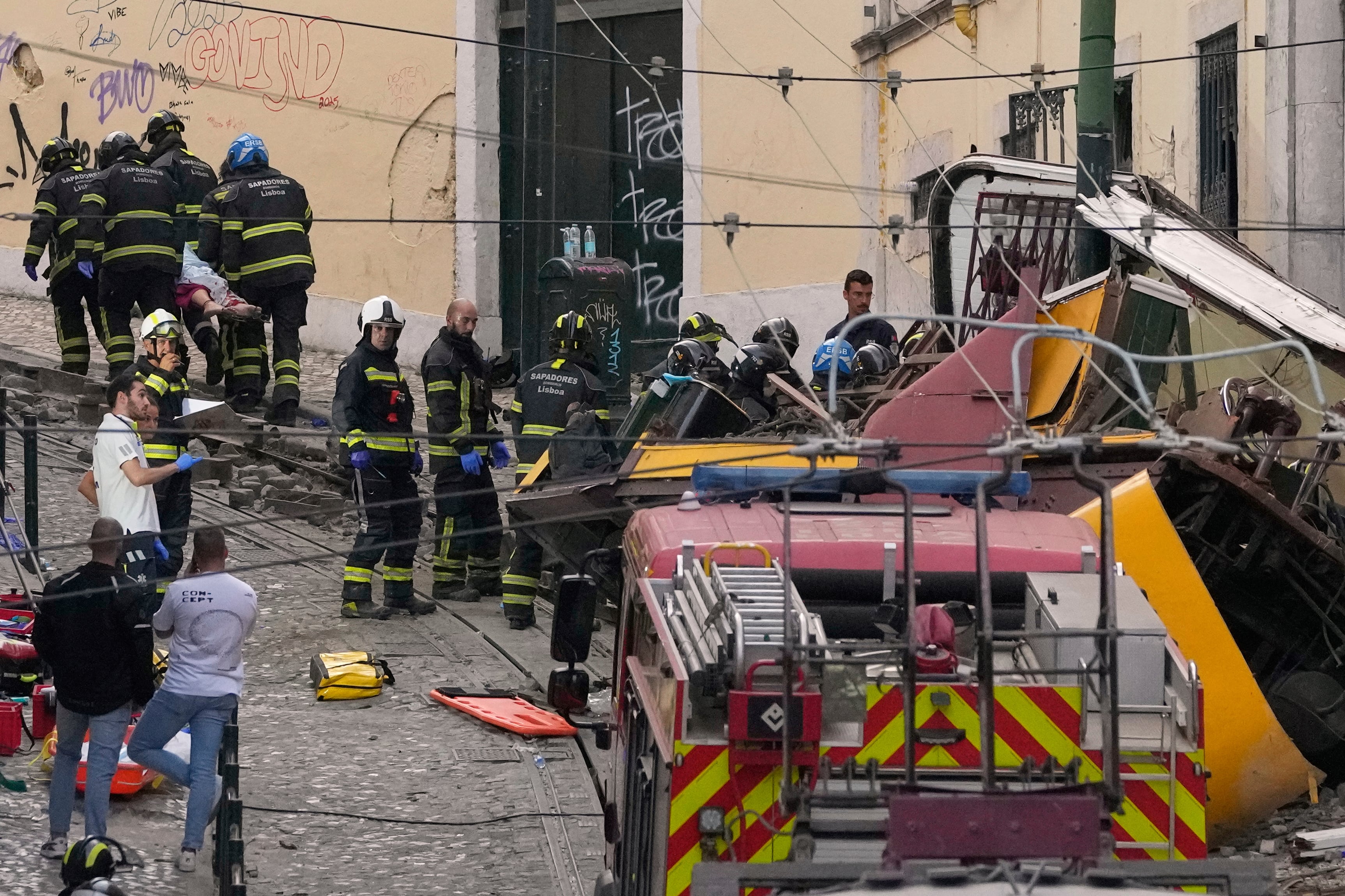 Firefighters carrying the body of a person on a stretcher at the site of a derailed electric streetcar in Lisbon, Portugal, Wednesday, Sept. 3, 2025.