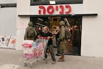 Nurit Kadosh, center, puts a hand on her chest as soldiers patrol the supermarket in Sderot a few minutes after a rocket hit the building on Oct. 9, 2023.