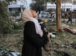 A woman reacts while holding a pillow as she stands amidst debris outside the site of the Ahli Arab hospital in central Gaza on Wednesday, Oct. 18, in the aftermath of an overnight blast there.