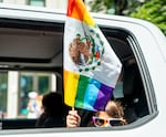 A child in the Portland Lesbian Choir’s lead car holds a rainbow Mexican flag out the back window.