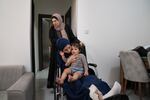 Raneem Hijazi holds her baby, Mariam, on her lap in her wheelchair, as Hijazi's mother-in-law, Soha Sakallah (standing), helps her.