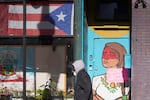 A pedestrian walks past the flag of Puerto Rico and the colorful door to the sanctuary apartment of Chicago's Adalberto Memorial United Methodist Church in Chicago in 2021. The church has provided shelter to immigrants in the U.S. illegally.
