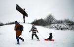 A lady is seen pulling her child along on a sledge as they admire Anthony Gormley's sculpture, the Angel of the North, which is surrounded by heavy snow in Gateshead, North East England, as the severe weather continues across England, on Sunday.