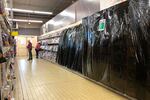 In this Monday, Nov. 2, 2020, a customer picks up a magazine in a supermarket in Gex, France. French supermarkets will be prohibited from selling books, make-up, clothes and other goods considered as non essential as smaller businesses have been forced to shut down amid virus lockdown. 