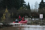 Rescue workers with Chehalis Fire venture into a flooded neighborhood to pick up evacuees after heavy rains, Tuesday, Dec. 9, 2025, in Chehalis, Wash.