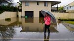 A woman stands in a flooded street Tuesday at Windsor on the outskirts of Sydney, Australia.