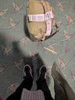 A green bag set at the feet of the photographer on the recognizable Portland airport carpet