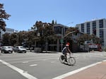 A bicyclist pedals through a four-way intersection on a sunny day in Eugene.