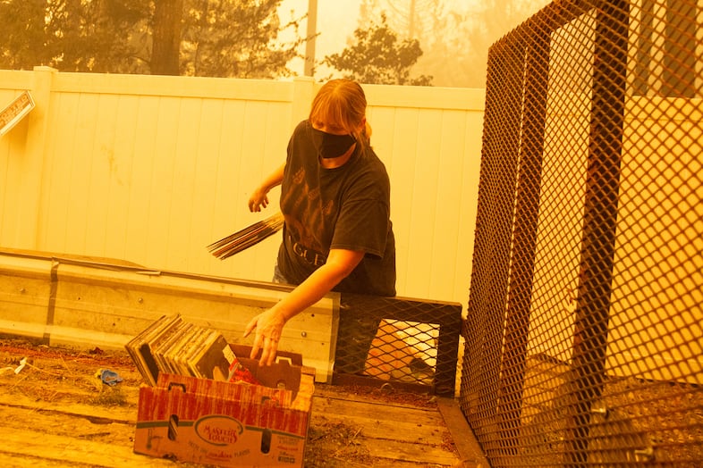 Chelsea DeVos tosses vinyl records from a trailer as the Santiam Fire approaches near Gates, Ore., Sept. 9, 2020. Joshua Graham and Nicolaus Noack (not pictured) of CERT helped transport DeVos' animals and valuables from her property.