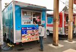 José Perez points out menu choices to a customer in front of his Cuban food cart, Qué Bola?, at the Portland Mercado in Southeast Portland.