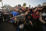 Displaced Palestinian struggle to receive donated food for iftar, the fast-breaking meal, on the first day of the Muslim holy month of Ramadan at a community kitchen in Khan Younis, Gaza Strip, Wednesday, Feb. 18, 2026.