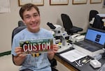 Marek Stanton with the "Pollinator Paradise" license plate he designed.