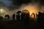 Protesters use umbrellas to shield themselves from impact munitions after federal law enforcement deploy tear gas outside the Mark O. Hatfield federal courthouse in Portland, Ore., Monday, July 20, 2020.