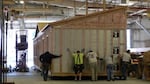 Workers at Blazer Industries push a half-built portable classroom out the door of the modular building manufacturing plant in Aumsville, Oregon.