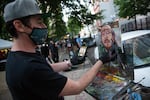 Jonathan Luczycki paints Donavan La Bella across from the Mark O. Hatfield federal courthouse in Portland, Ore., July 22, 2020. La Bella is in recovery weeks after federal officers shot him in the head with so-called "less lethal" munitions.