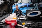 Danny Borski, head of vehicle testing at Daimler Truck North America, shows the engine of a semi-truck on display.