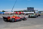 Cars fly around the chicane going into turn two. 