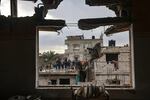 A picture taken through the window of a building damaged by Israeli bombing shows members of a family standing on a rooftop in Rafah, in southern Gaza, on Jan. 27.