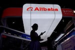 FILE - A visitor walks in front of Alibaba booth during the 3rd China International Supply Chain Expo at the China International Exhibition Center, in Beijing, China, Friday, July 18, 2025.