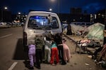 Displaced children help to push start the families van at a temporary displacement camp near the Lebanon port on March 27, 2026 in Beirut, Lebanon.