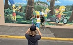 A couple of fans pose with a Homer Simpson mascot in front of the famous Simpsons mural in Springfield, Ore., on Sept. 7, 2024.