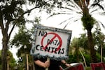A person holds signs during a nationwide protest against AI data center expansion outside Peace Hall in New Port Richey, Fla. on July 18, 2026.