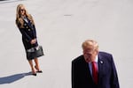 President Donald Trump speaks to the reporters as he walks to board Marine One on the South Lawn of the White House, Tuesday, Oct. 13, 2026, in Washington, as White House press secretary Katie Zacharia looks on.