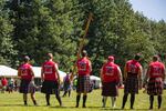 Caber-tossers watch a fellow competitor try to launch a 15-foot pole end-over-end.