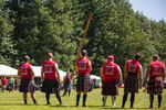 Caber-tossers watch a fellow competitor try to launch a 15-foot pole end-over-end.
