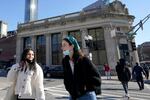 FILE - Passers-by wear masks under their chins as they chat with one another while crossing a street, in Boston, Wednesday, Feb. 9, 2022. Students and staff at public schools in Massachusetts will no longer be required to wear face coverings while indoors starting Feb. 28, state officials said Wednesday, Feb. 9, 2022. (AP Photo/Steven Senne, File)
